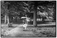 406336 Afbeelding van een wandelaar met een paraplu in het singelplantsoen aan het Servaasbolwerk te Utrecht.